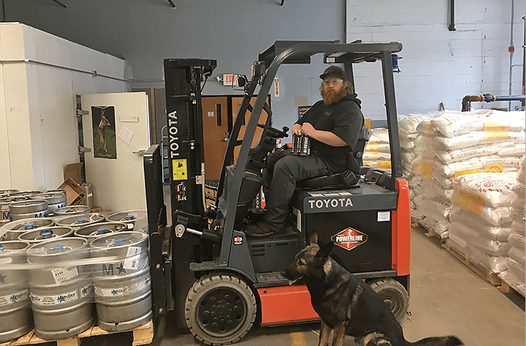 Forklift operator wearing grey 1620 Double Knee Cargo pant while moving pallets with forklift